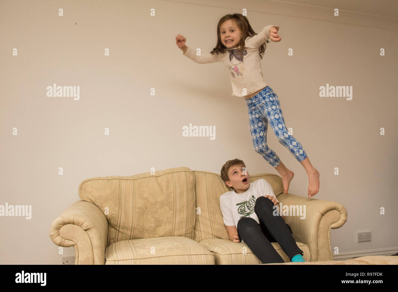 children, brother and sister jumping about on furniture, diving and leaping, being hyperactive, lots of energy, playing together Stock Photo