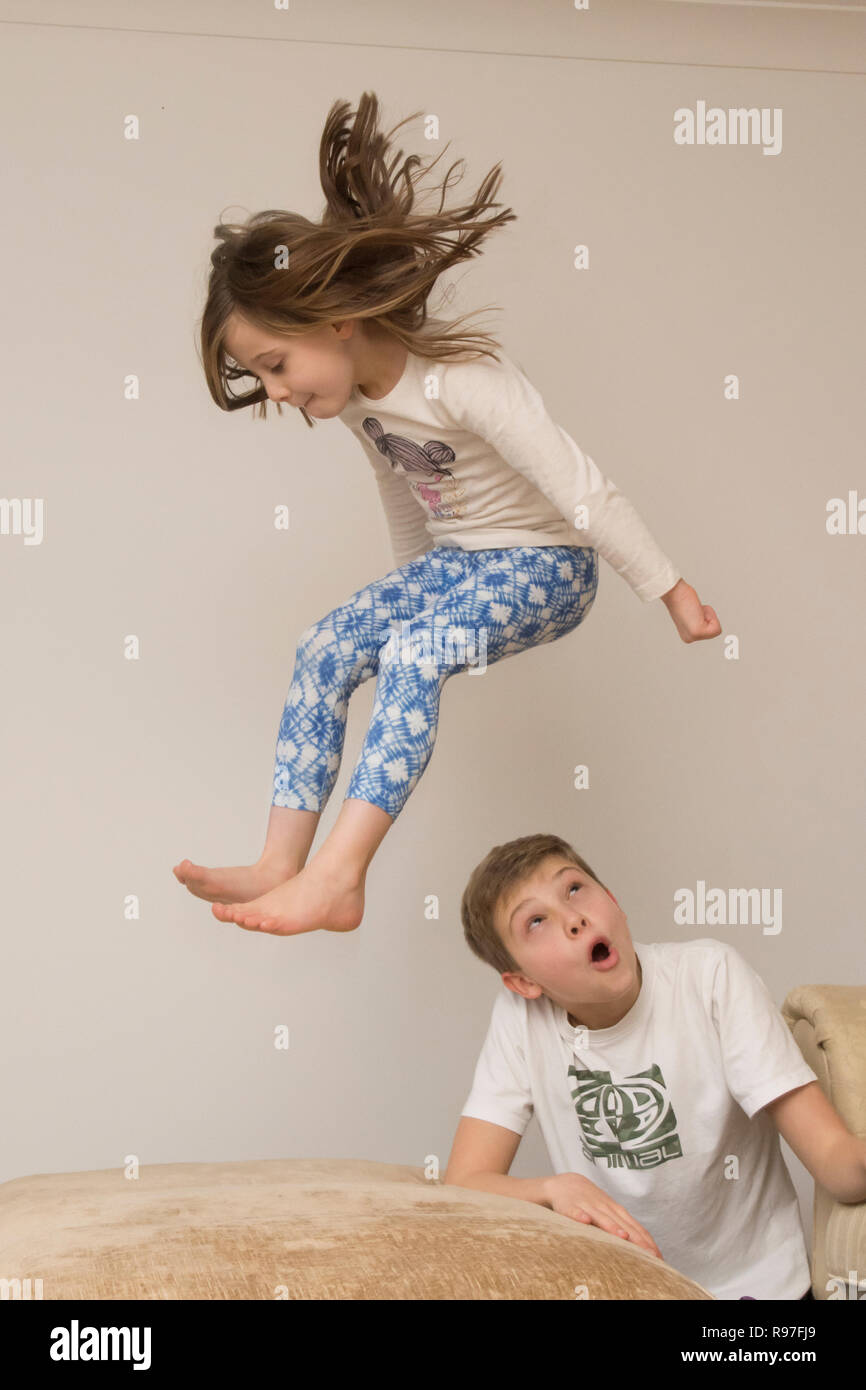 children, brother and sister jumping about on furniture, diving and leaping, being hyperactive, lots of energy, playing together Stock Photo