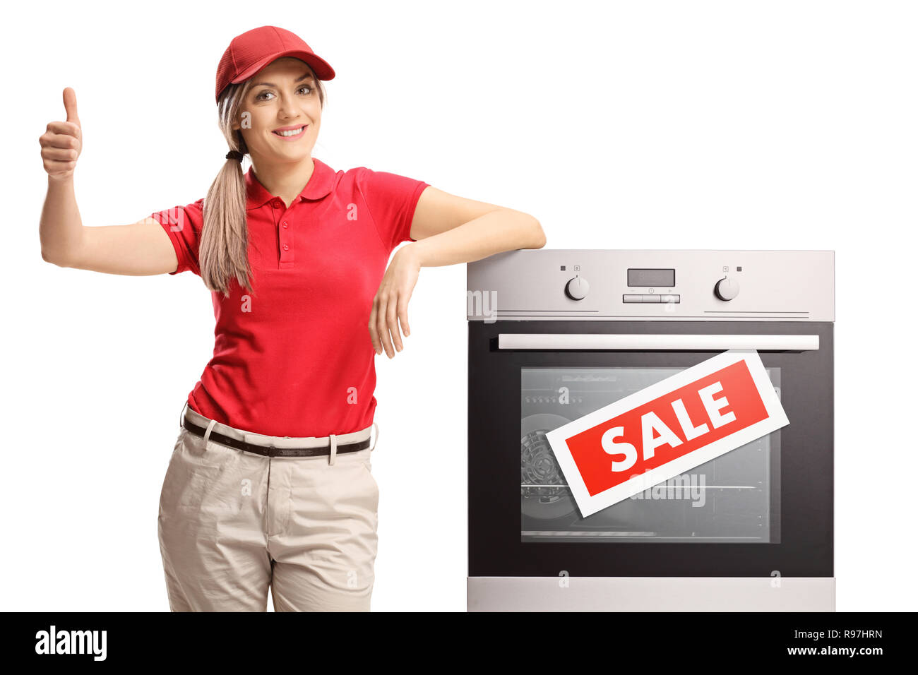 Saleswoman leaning on an electrical oven on sale and giving thumb up isolated on white background Stock Photo