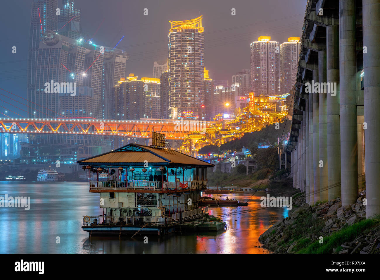 Night view of a boat on the Yangtze River with high rise city buildings in the distance in Chongqing, China Stock Photo