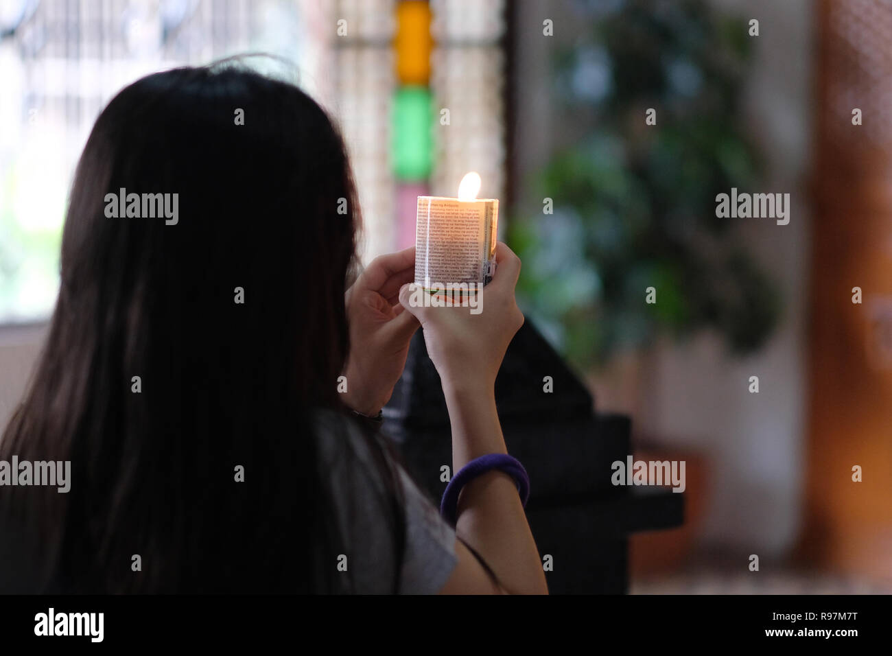 A Filipino woman lights candle inside the Roman Catholic Antipolo Cathedral or National Shrine of Our Lady of Peace and Good Voyage located in the city of Antipolo, in the province of Rizal in the Philippines. Stock Photo