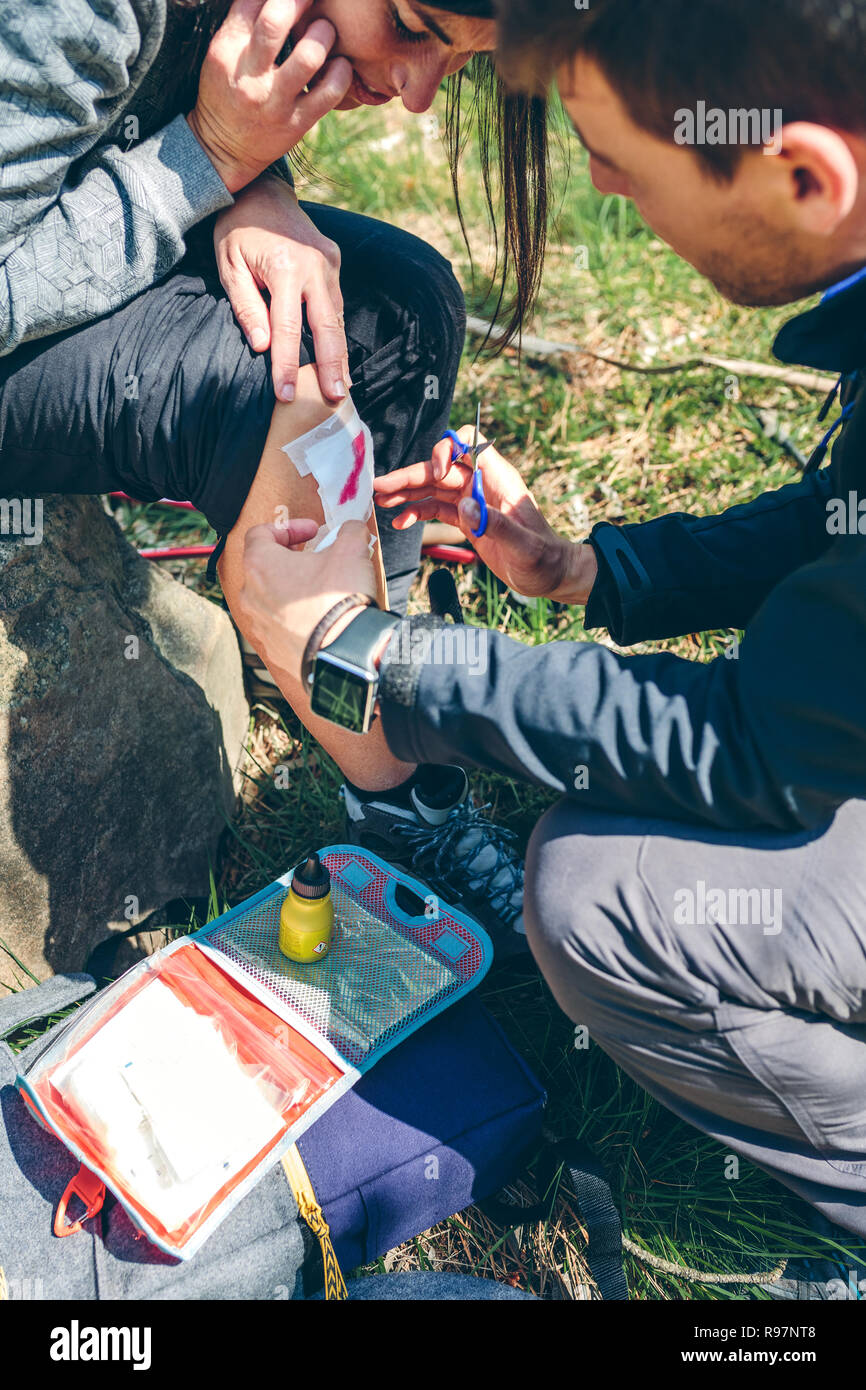 Man healing knee to woman who has been injured trekking Stock Photo