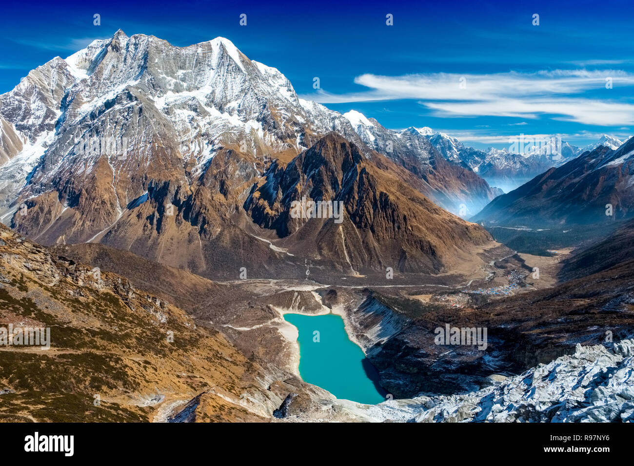 Glacial lake, mountains and the village of Samagao on the Manaslu Circuit trekking route, Nepal Stock Photo