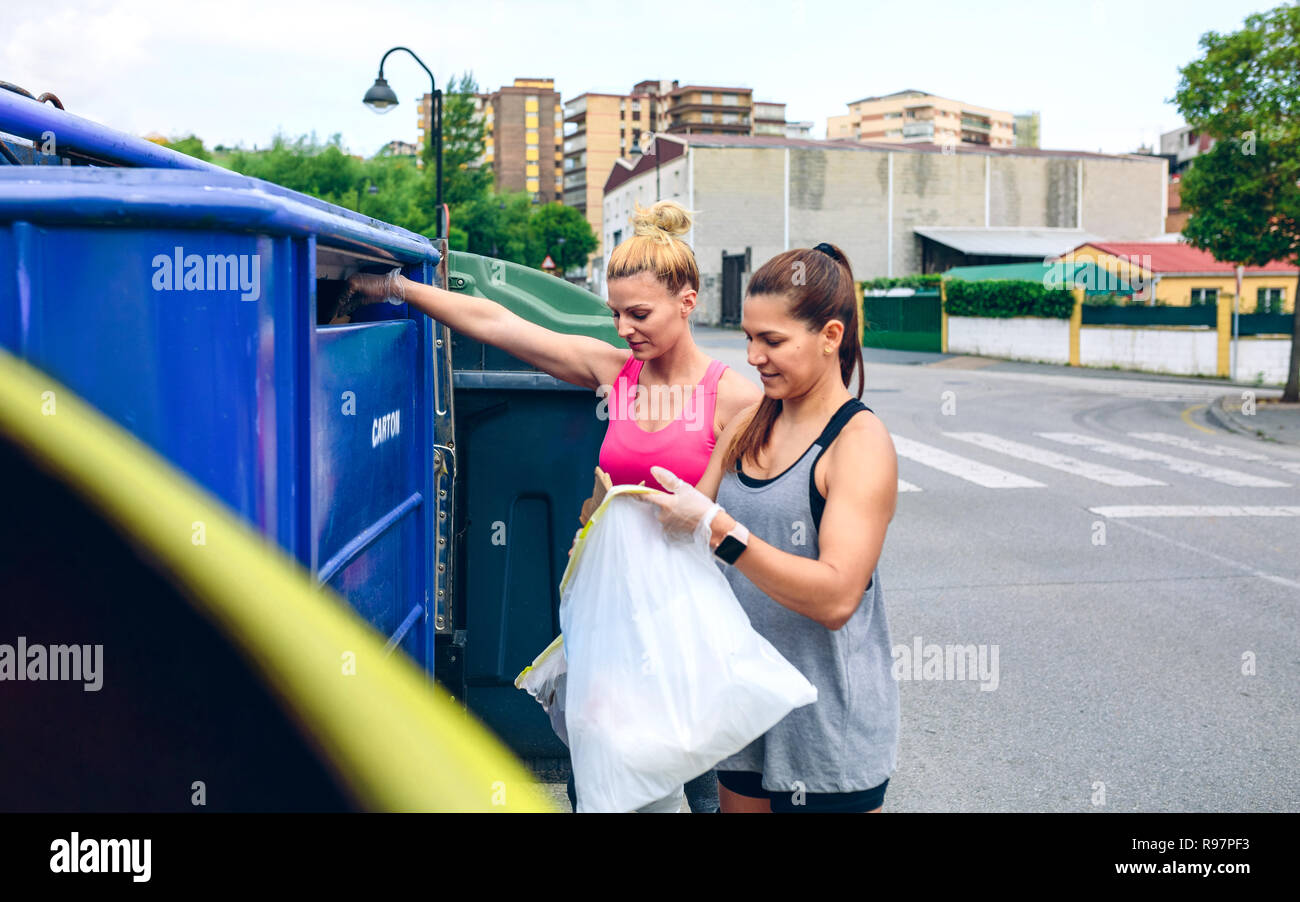 Girls throwing garbage to recycling dumpster Stock Photo Alamy