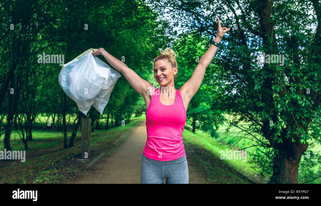Girl arms up showing garbage bags doing plogging Stock Photo