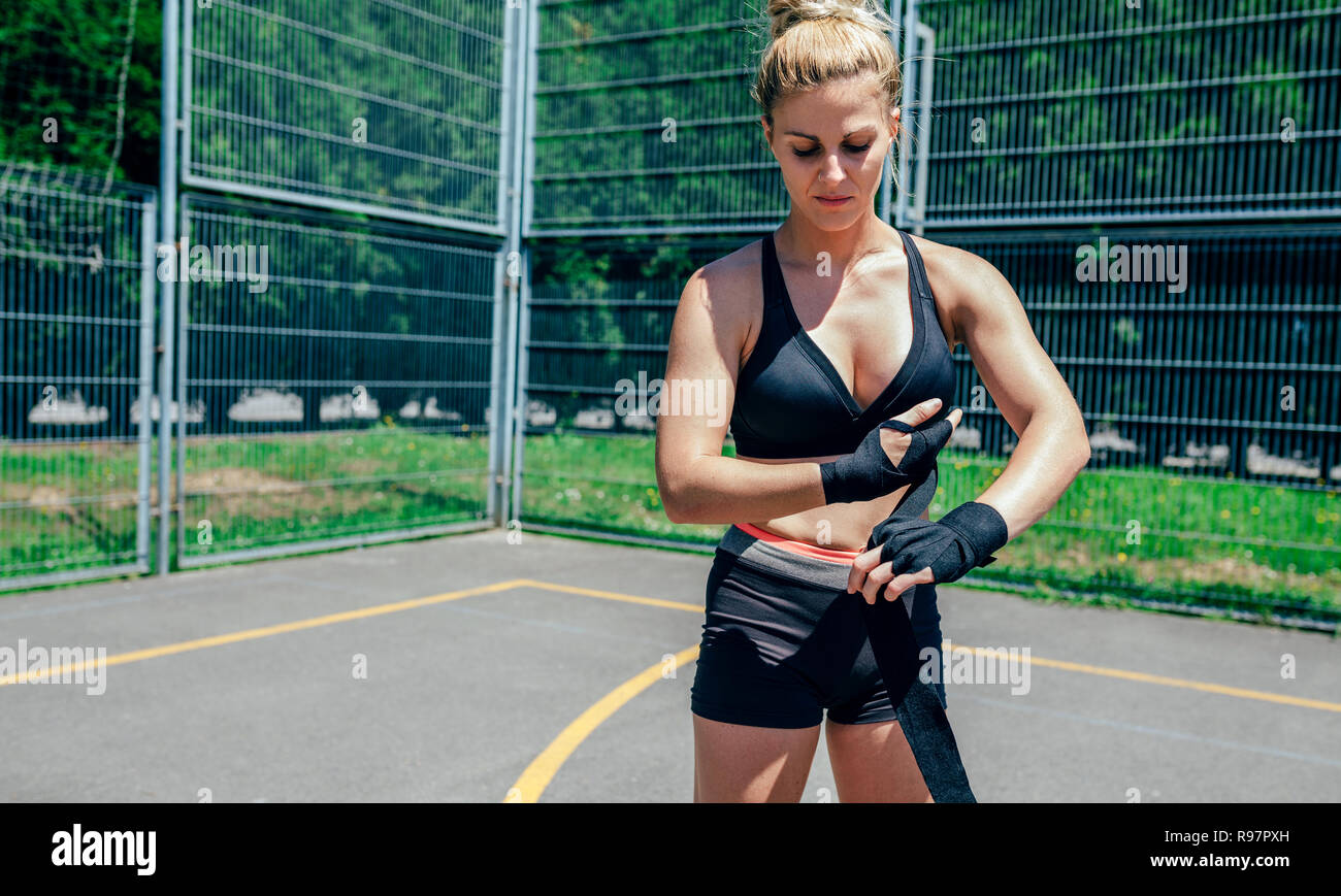 Sportswoman putting on boxing bandages Stock Photo