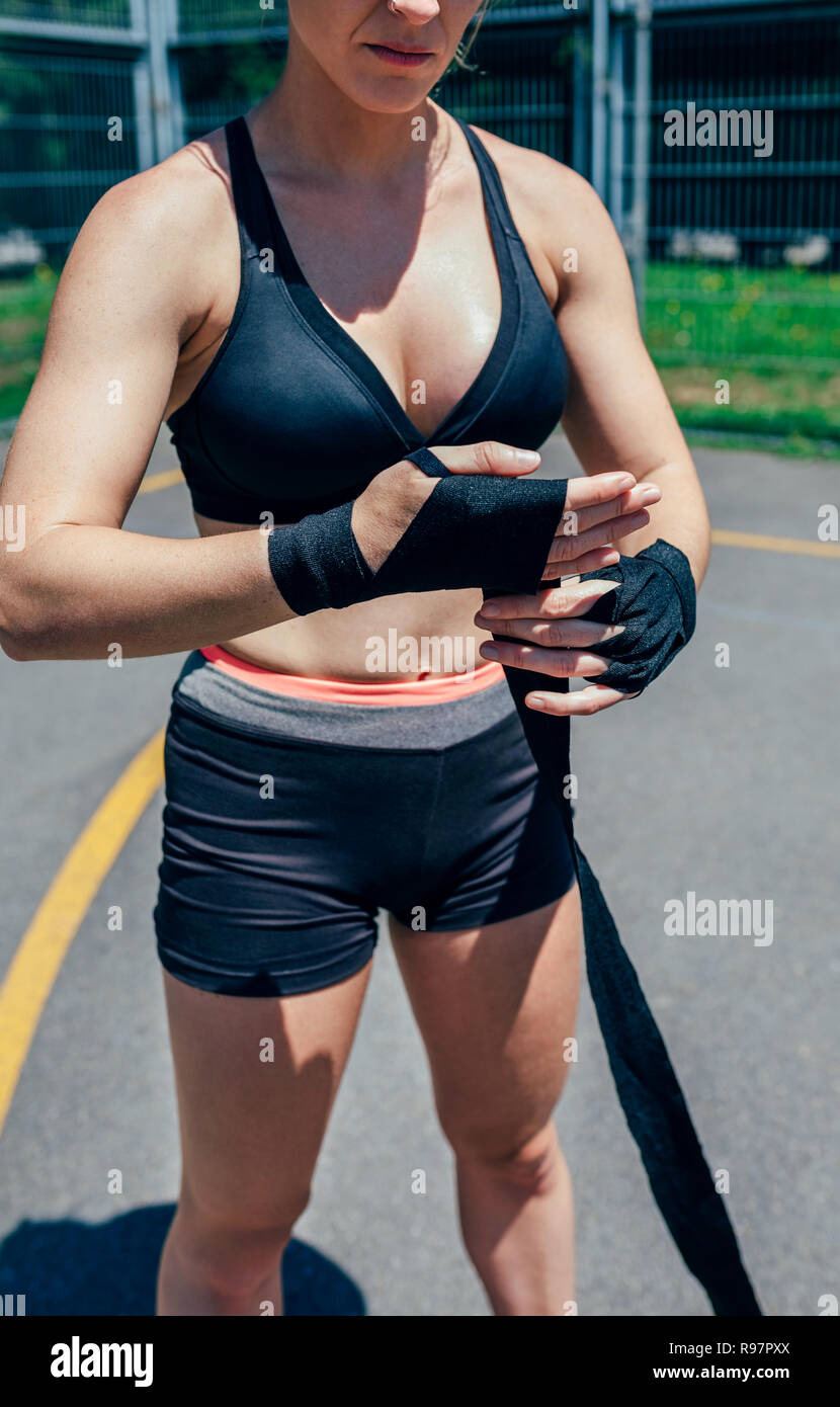 Sportswoman putting on boxing bandages Stock Photo