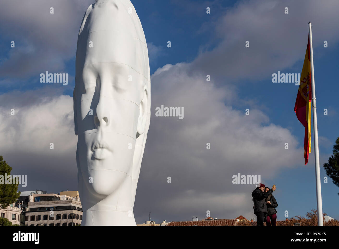 Couple taking a selfie with Julia, white marble sculpture by Jaume Plensa in Plaza Colon, Madrid, Spain Stock Photo