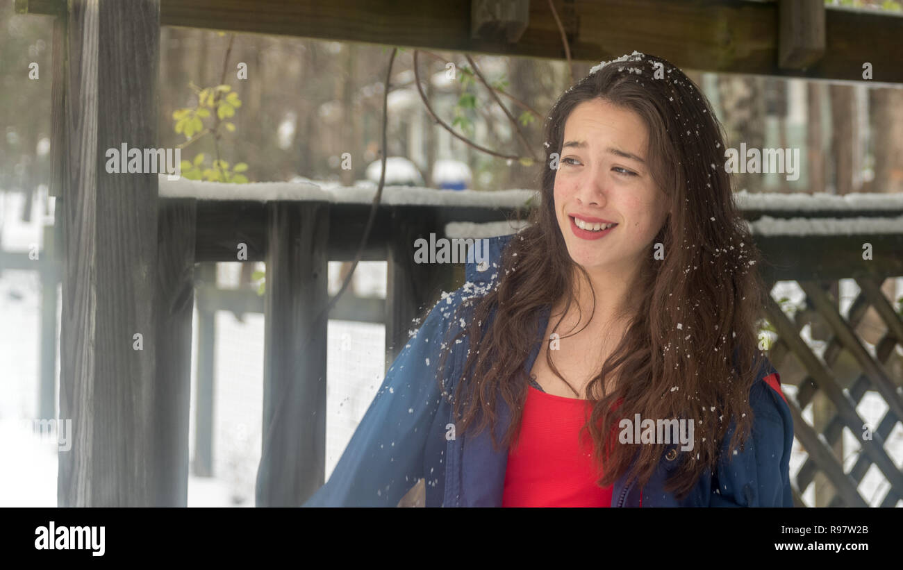 Young asian teen with red dress standing in snow and smiling Stock Photo