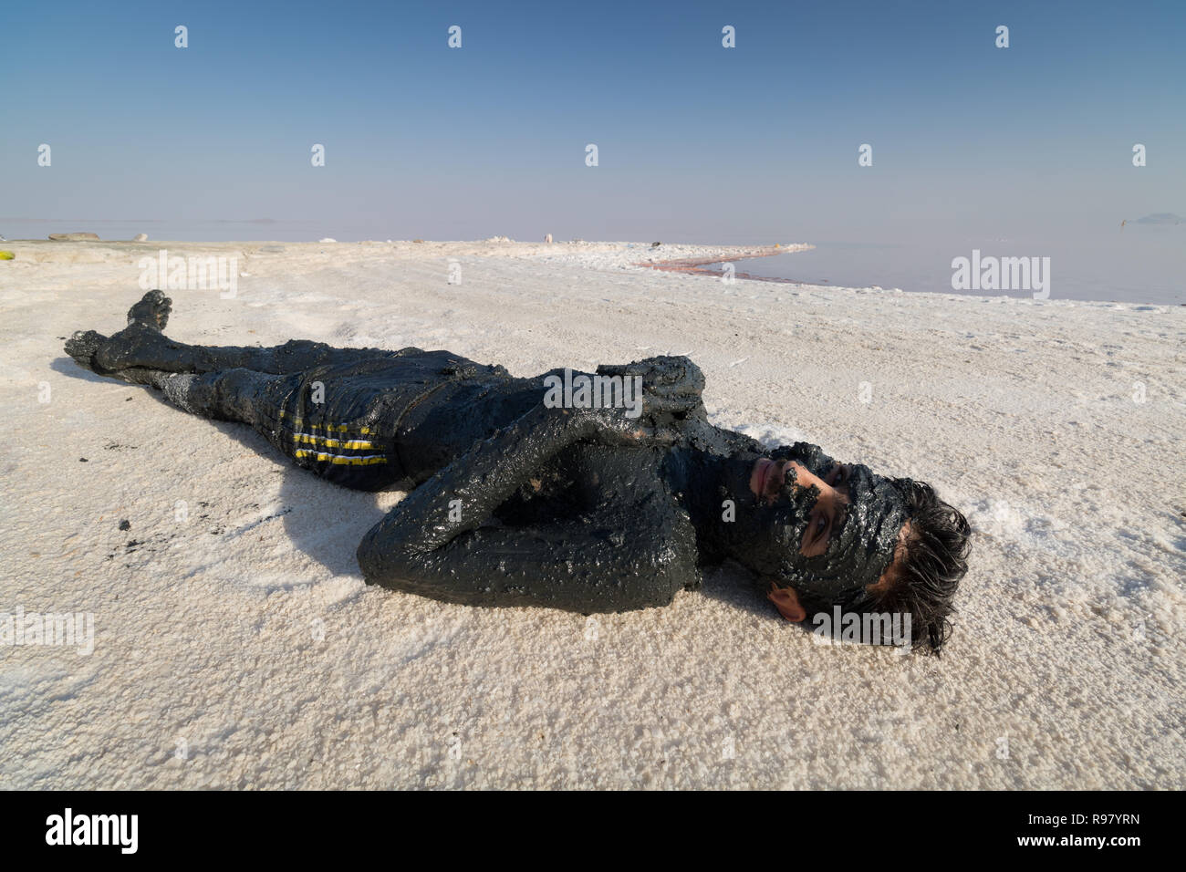 Urmia lake-A man coats himself in black mud at Lake Urmia, a salt lake in the province of West Azerbaijan. Stock Photo