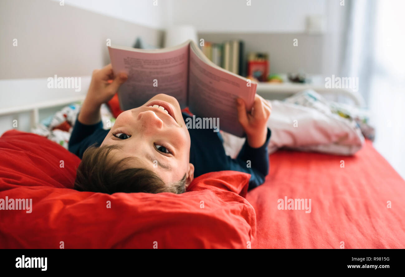 Boy looking camera while reading a book Stock Photo