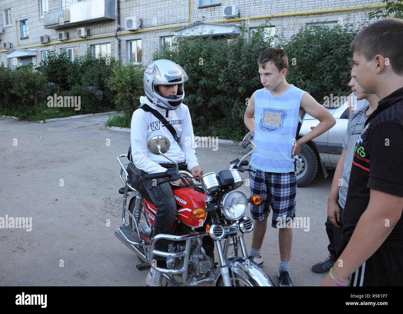 Kovrov, Russia. 18 August 2013. Teens communicate to his friend who are riding a motorcycle Orion in the courtyard of a multi-storey residential build Stock Photo