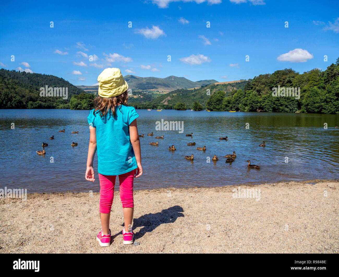 Girl standing by ducks on Lac Chambon in Auvergne, France Stock Photo