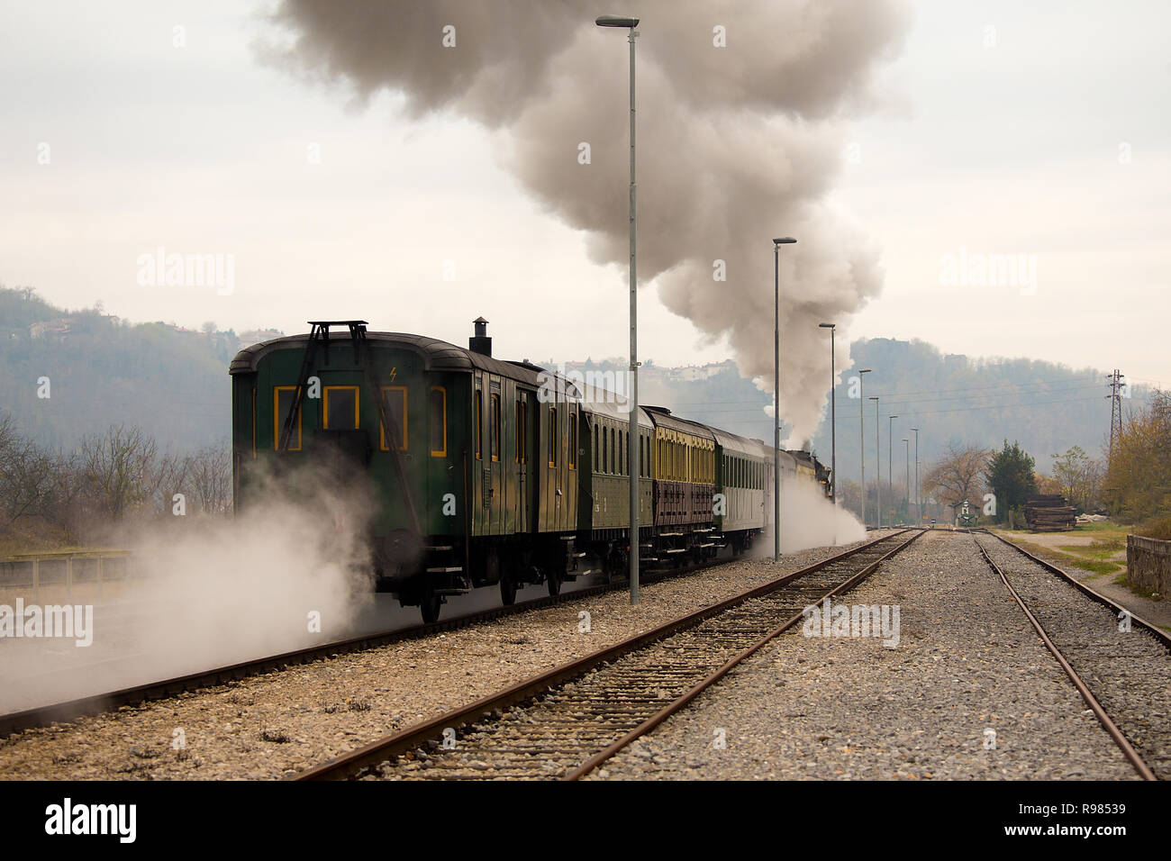 Old steam train leaving the railway station in Nova Gorica, Slovenia, Europe. Lots of black and gray steam hiding the locomotive Stock Photo