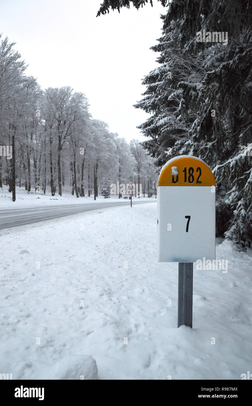 A milestone on a slippery snowy mountain road in winter Stock Photo