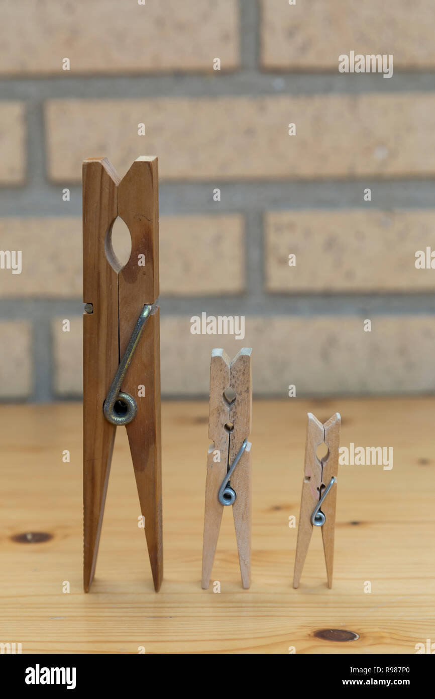 three clothespins of different sizes placed side by side in progression Stock Photo