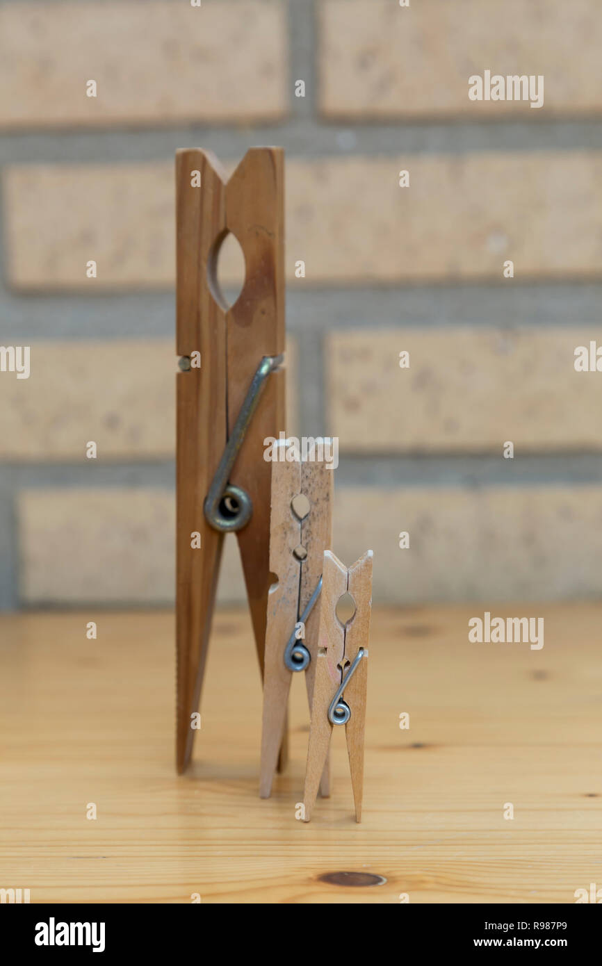 three clothespins of different sizes placed side by side in progression Stock Photo