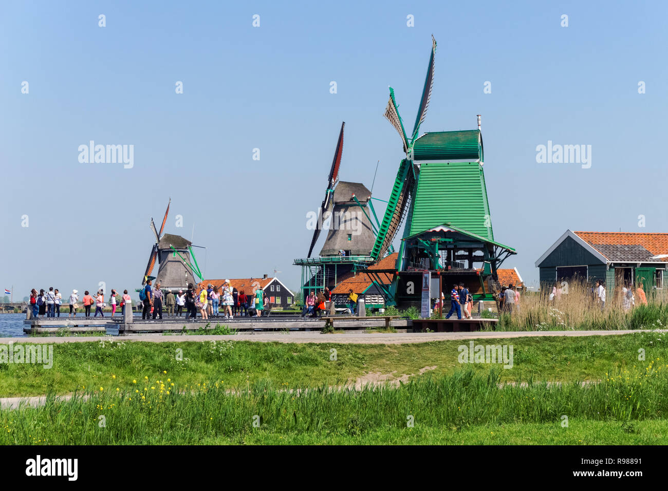 Tourists walking along traditional dutch windmills at Zaanse Schans in Netherlands Stock Photo
