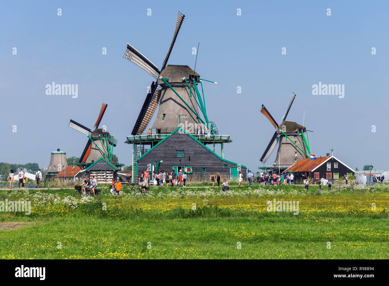 Tourists walking along traditional dutch windmills at Zaanse Schans in Netherlands Stock Photo
