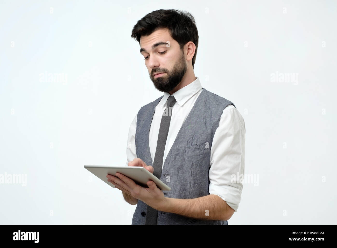 Pensive young handsome man using his digital tablet surfing in internet Stock Photo