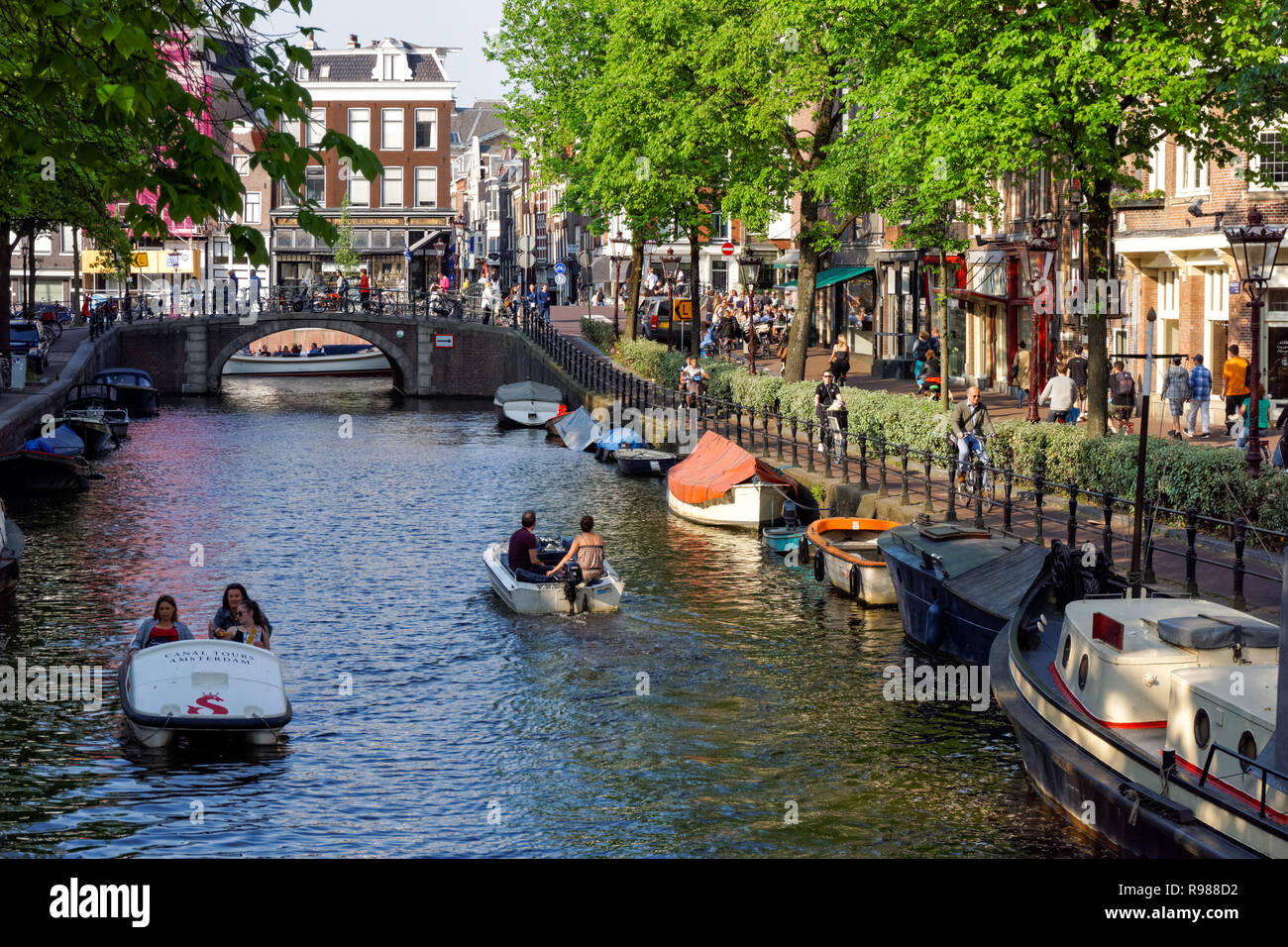 People cycling along Spiegelgracht canal in Amsterdam, Netherlands Stock Photo