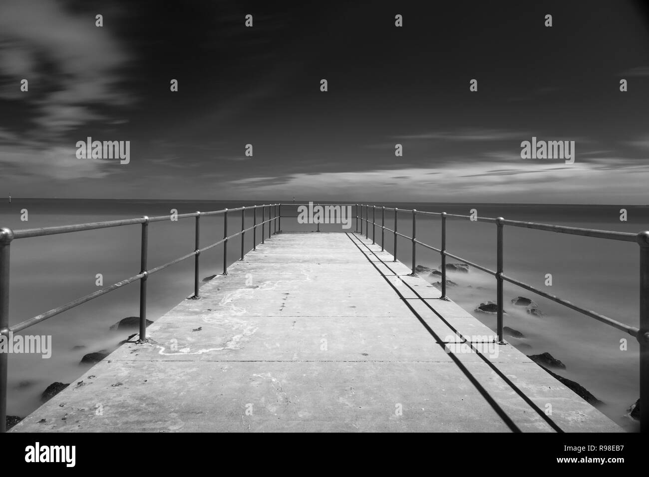 Jetty leading out into the bay, lit by moonlight, ling exposure at night, B&W Stock Photo