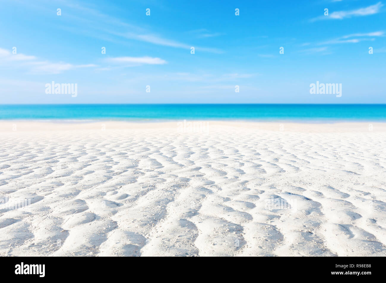 White sand curve or tropical sandy beach with blurry blue ocean and blue sky background image for nature background or summer background. Stock Photo