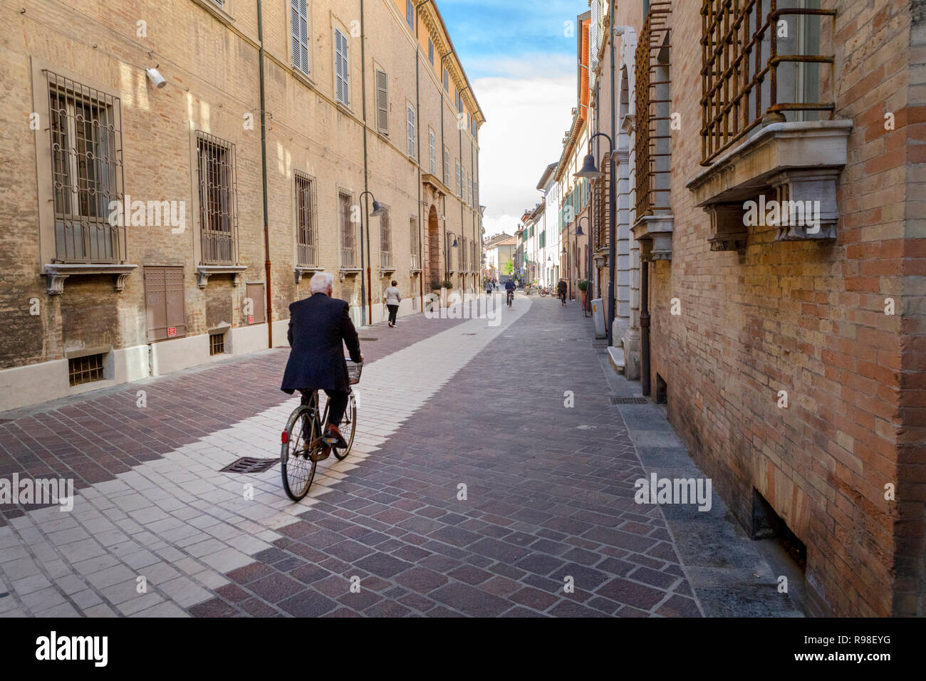 An elderly cyclist explores the relaxing streets of Ravenna, Italy, a pursuit which is beneficial for improved mental and cardiovascular health Stock Photo