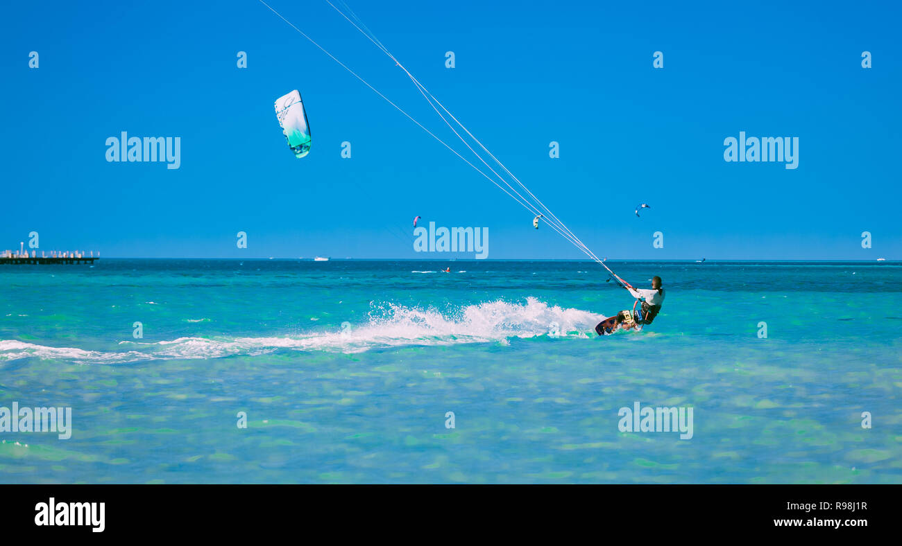 Egypt, Hurghada - 30 November, 2017: The kiteboarder holding the kite straps and gliding over the Red sea surface on the board. Professional sport act Stock Photo