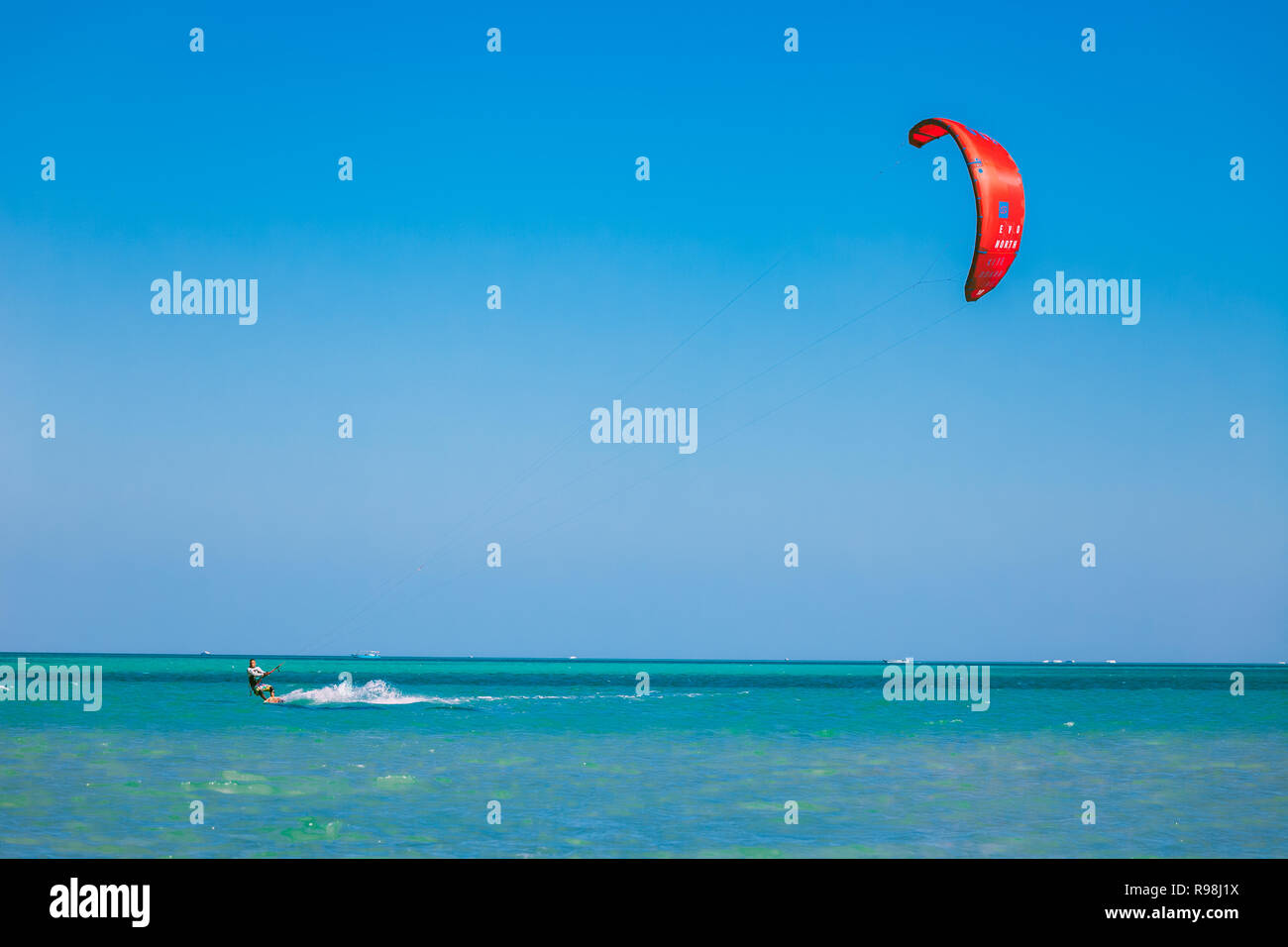 Egypt, Hurghada - 30 November, 2017: The kitesurfer with red kite gliding over the Red sea surface. Overwhelming marine scenery. The lone kiteboarder  Stock Photo