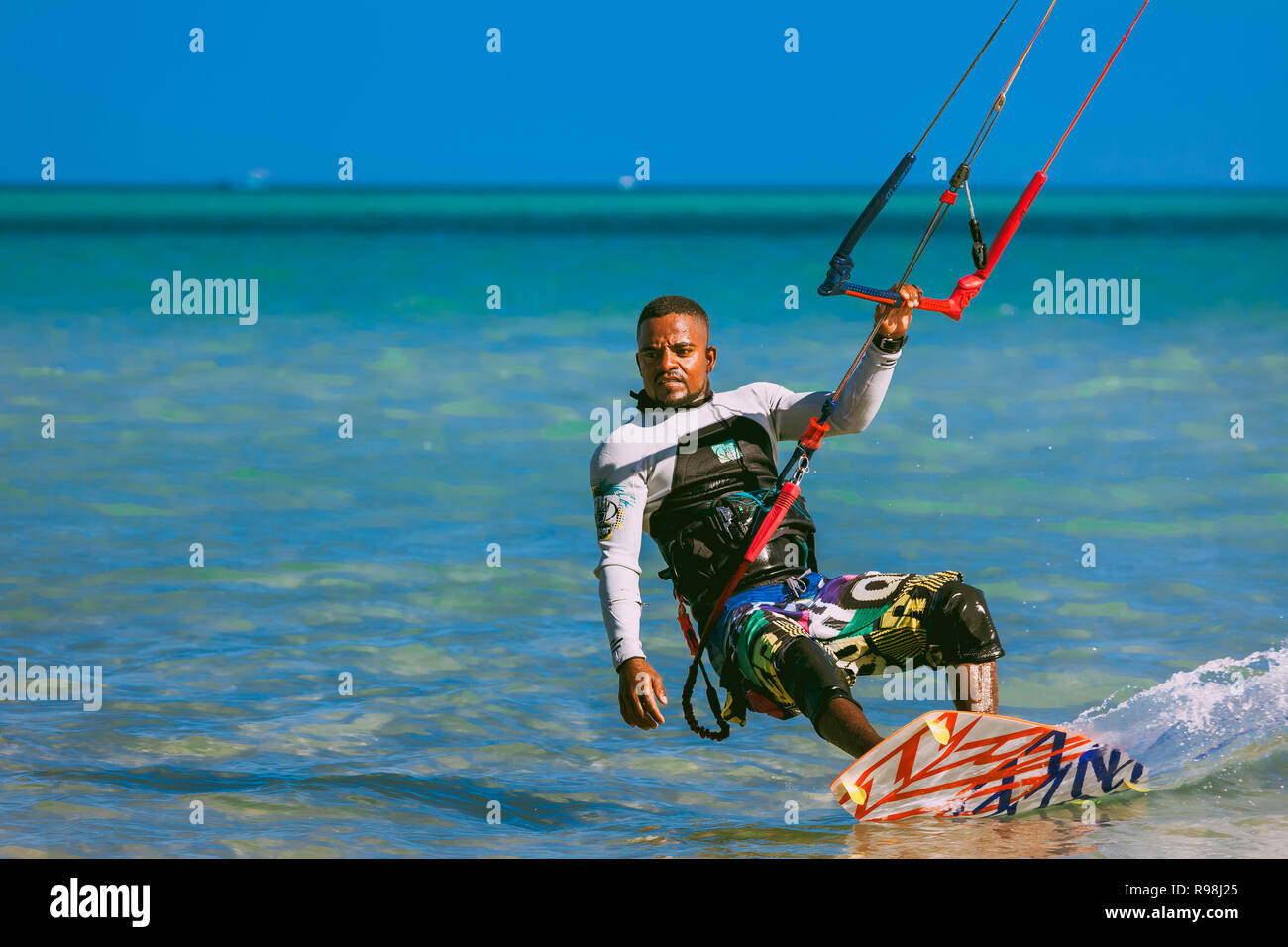 Egypt, Hurghada - 30 November, 2017: Close-up surfer with kite equipment standing on the surfboard. The Red sea shore. Unidentified Arab man surfing o Stock Photo