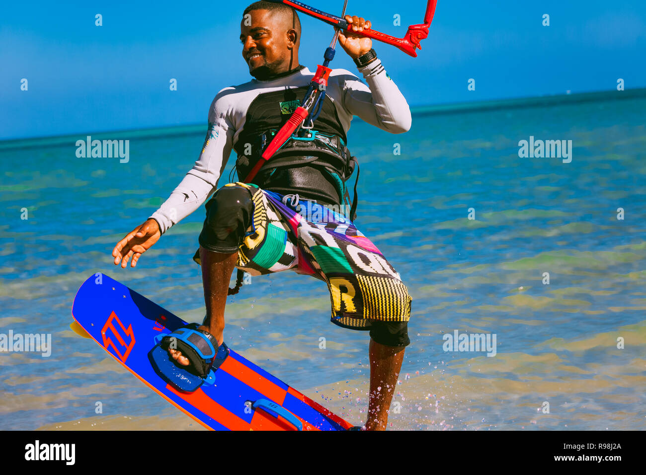 Egypt, Hurghada - 30 November, 2017: Close-up smiling kitesurfer soaring over the Red sea surface. The sportsman on the wakeboard holding the kite str Stock Photo