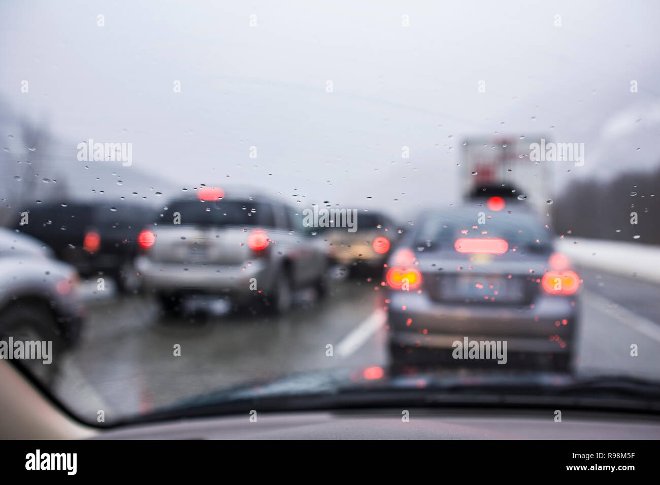 Looking out the wet windshield of a car at other cars  on a crowded roadway. Stock Photo