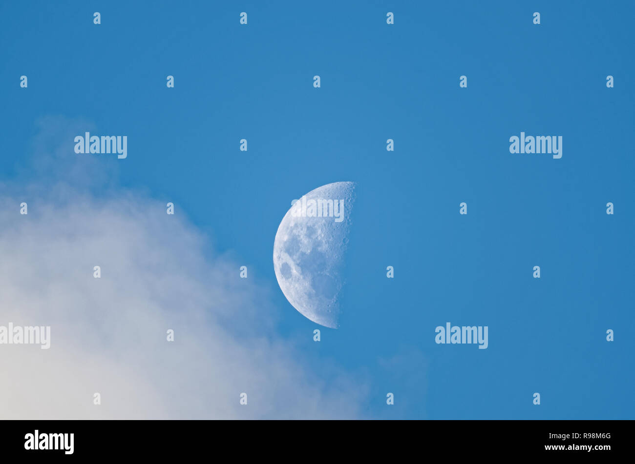 zoom to the moon during the day a cloud is going through Stock Photo