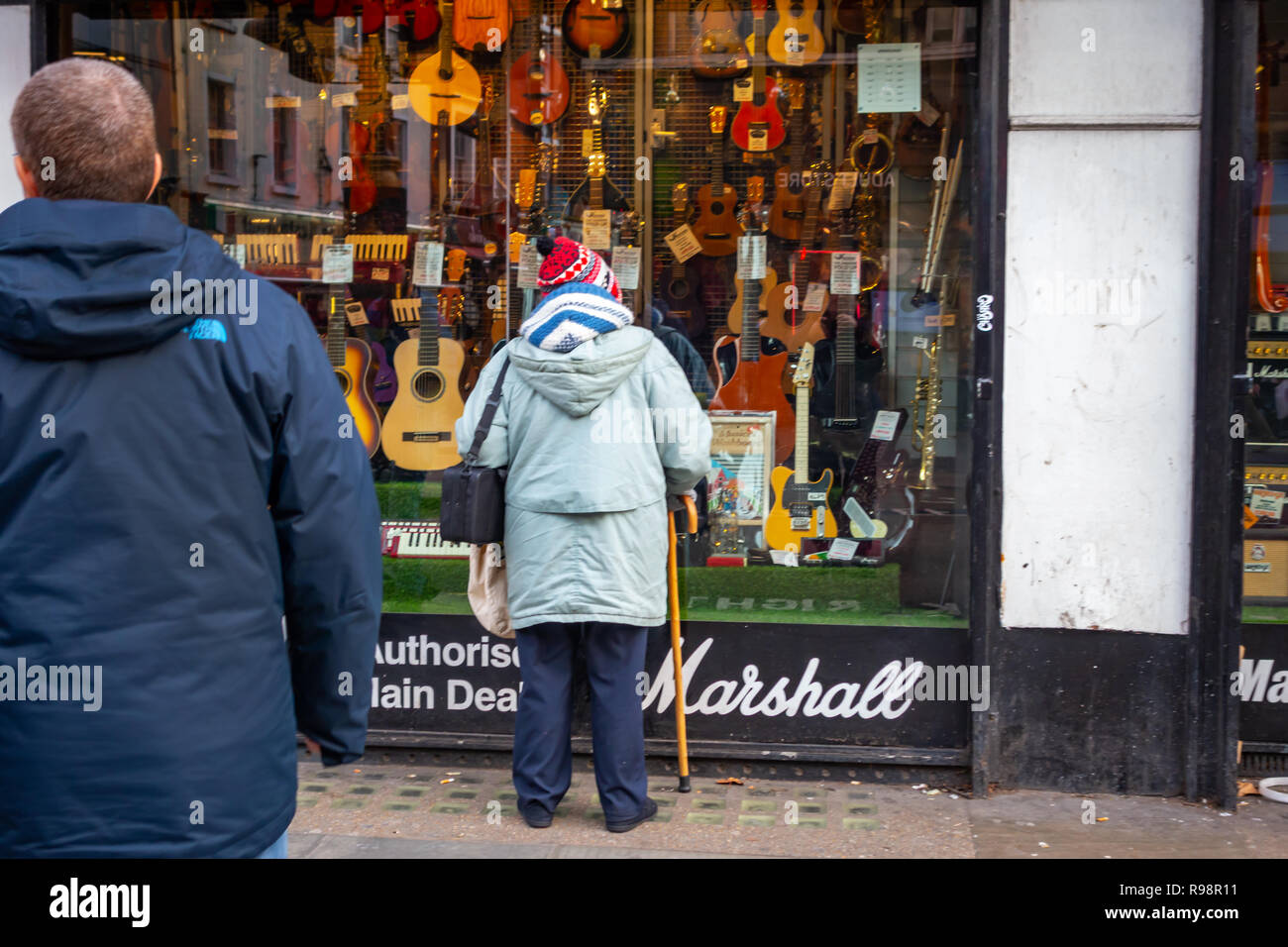 Older lady looking into the store shop front of Famous Macaris Musical