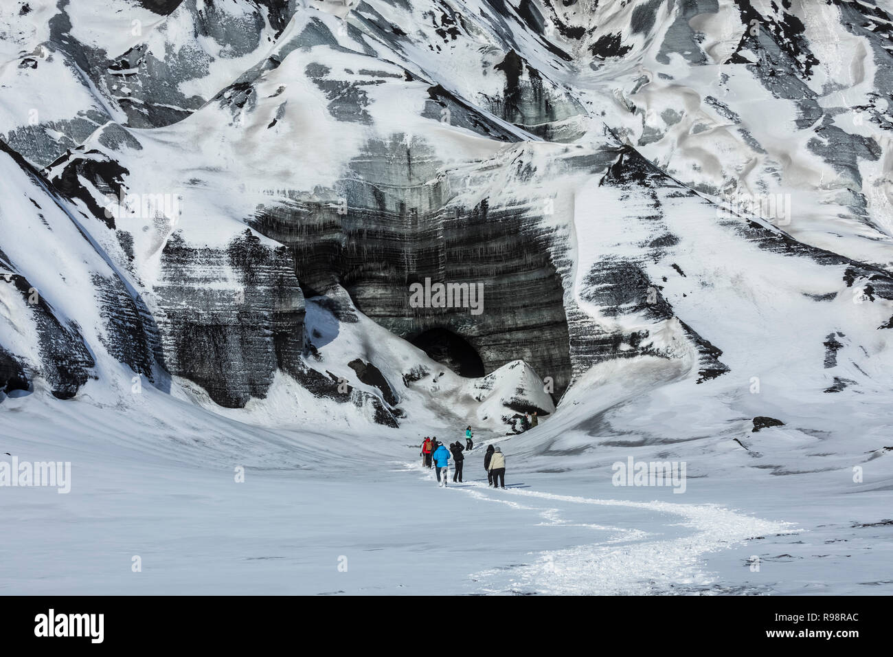 Adventurers walking on an ice cave tour to a lobe of Mýrdalsjökull Glacier, which sits atop Katla Volcano, in winter in Iceland [No model releases; av Stock Photo