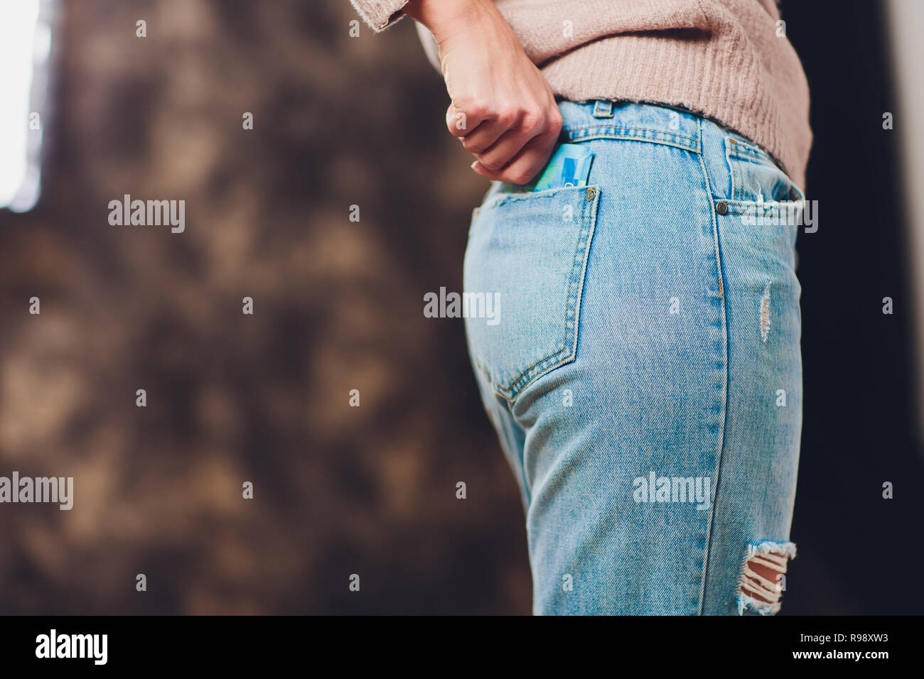 girl puts money in a pocket of jeans back paper bills 200 and 2000