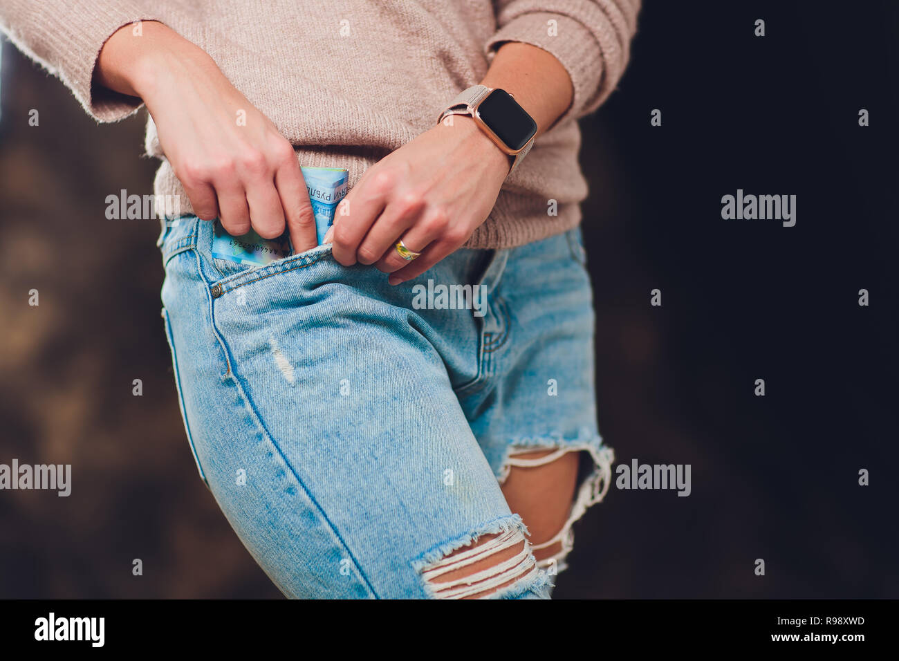girl puts money in a pocket of jeans back paper bills 200 and 2000