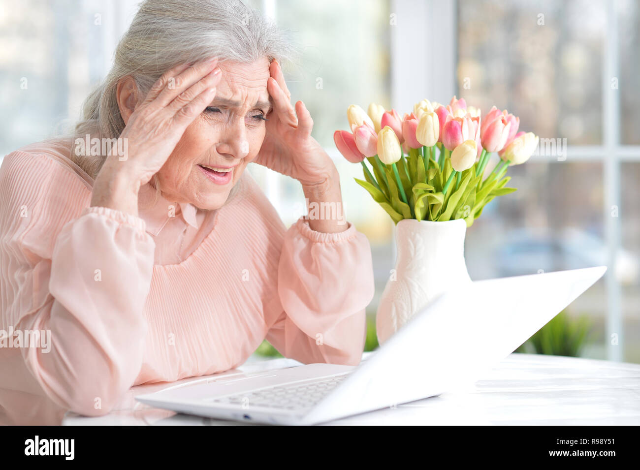Close up portrait of emotional senior woman with laptop Stock Photo