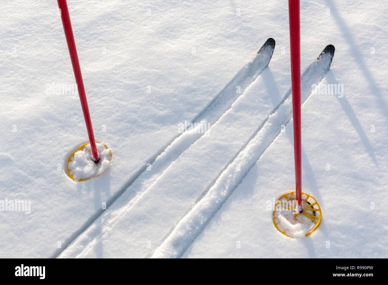 Off-track cross-country skis and red ski poles on untouched clean white snow. Stock Photo