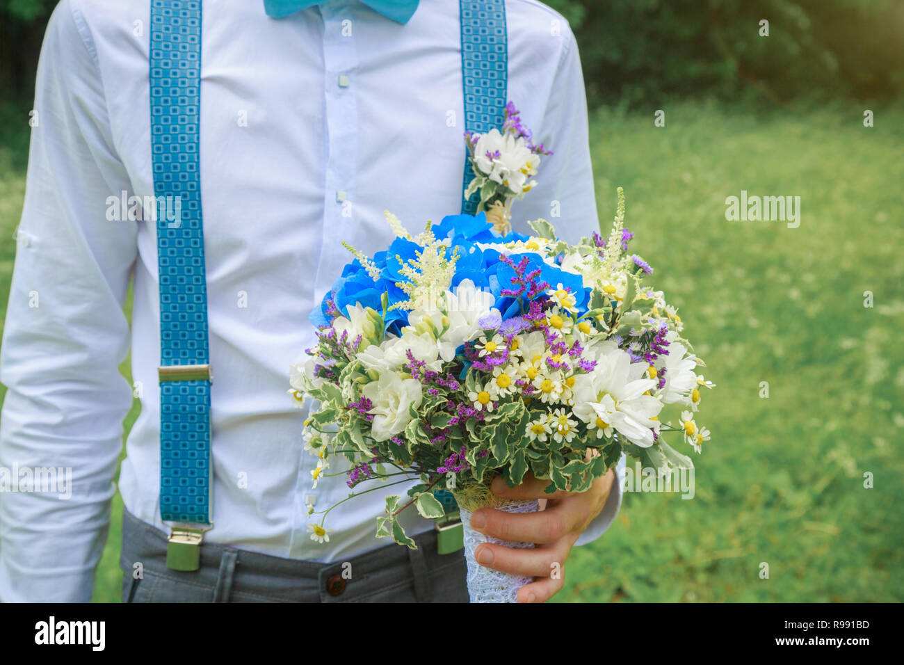 Groom holds a beautiful bouquet of flowers in his hand. Wedding in a ...