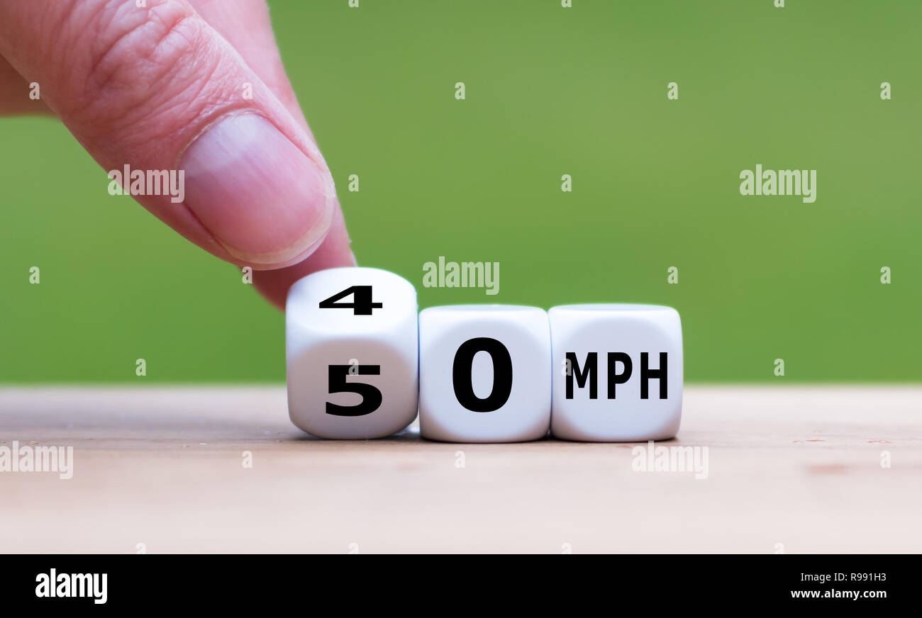 Hand is turning a dice and changes the expression '50 MPH' to '30 MPH' as symbol to reduce the speed limit from 50 to 30 miles per hour Stock Photo