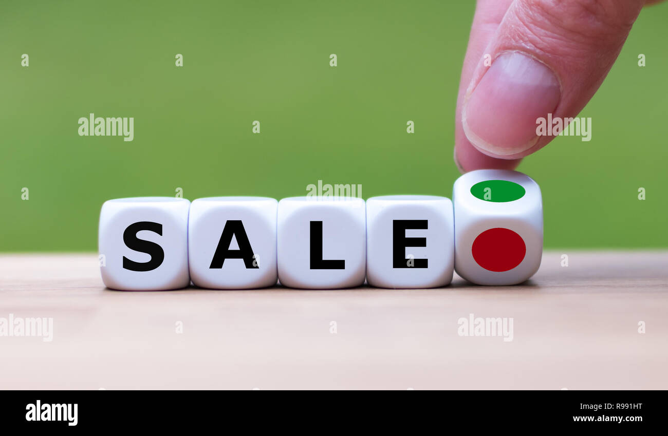 Hand is turning a dice and changes the color of a dot from red to green symbolizing the start of a sale Stock Photo