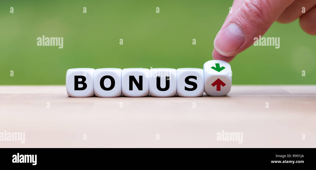 Hand is turning a dice and changes the direction of an arrow symbolizing that the bonus is going up (or vice versa) Stock Photo