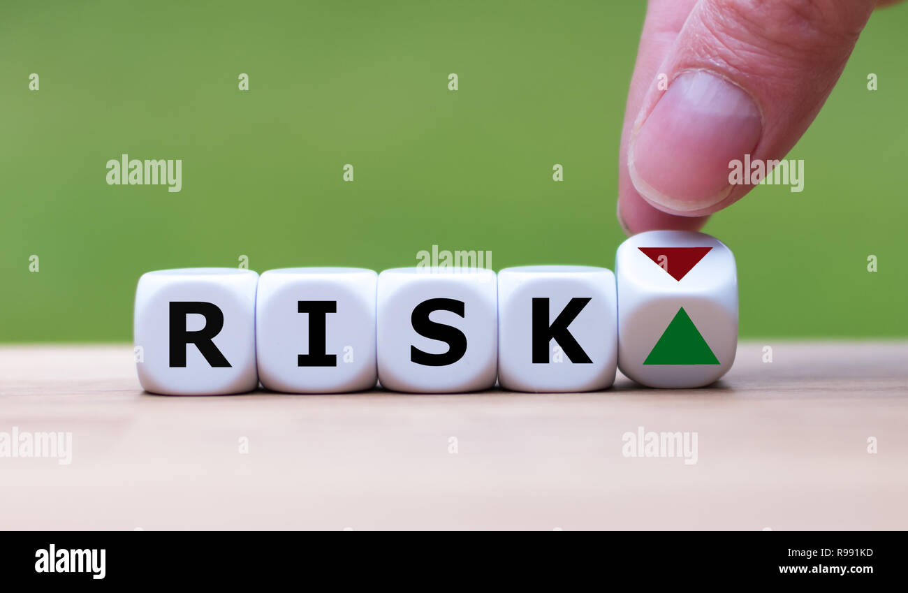 Hand is turning a dice and changes the direction of an arrow symbolizing that the risk is going up (or vice versa) Stock Photo