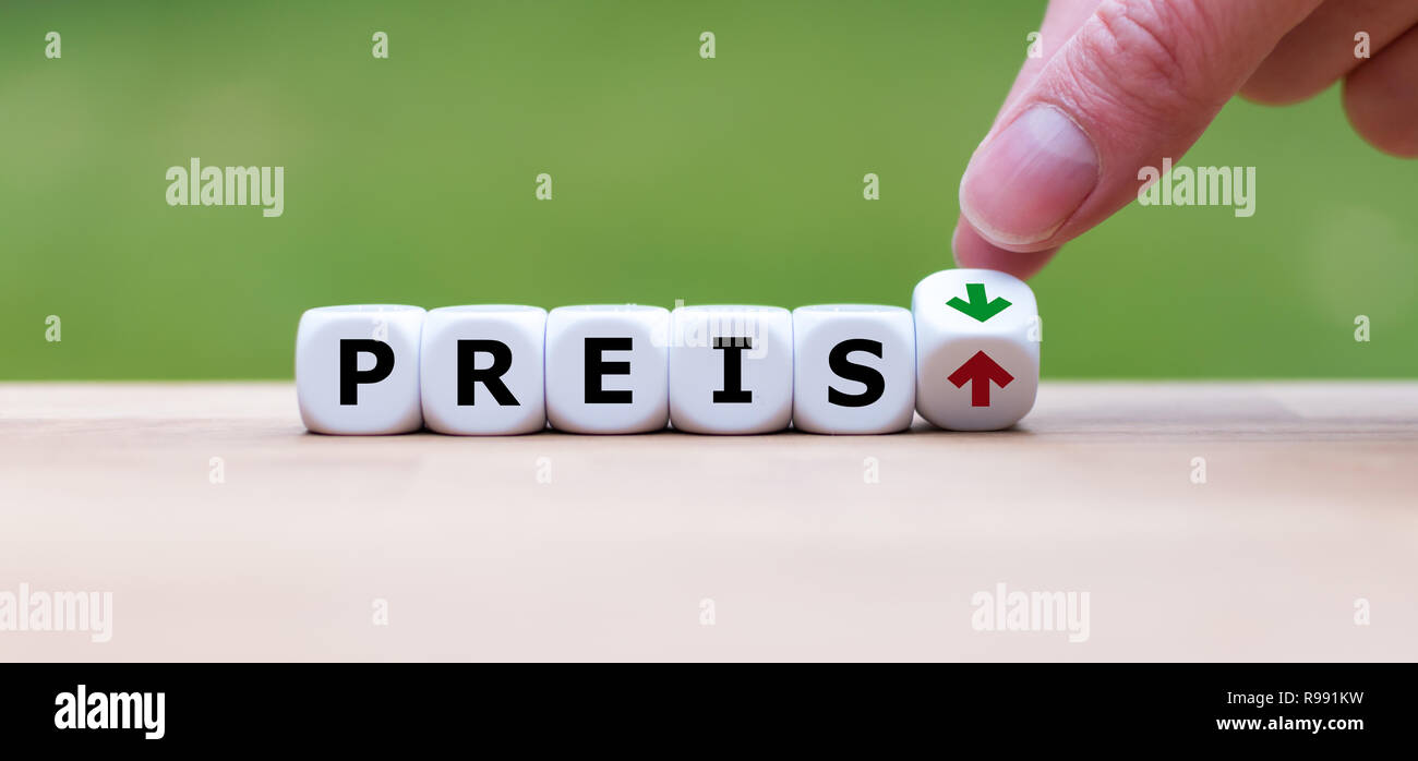 Hand is turning a dice and changes the direction of an arrow symbolizing that the price ('Preis' in german) is going down (or vice versa) Stock Photo
