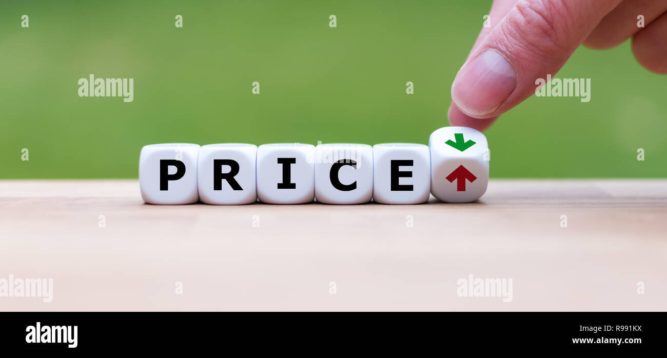 Hand is turning a dice and changes the direction of an arrow symbolizing that the price is going down (or vice versa) Stock Photo