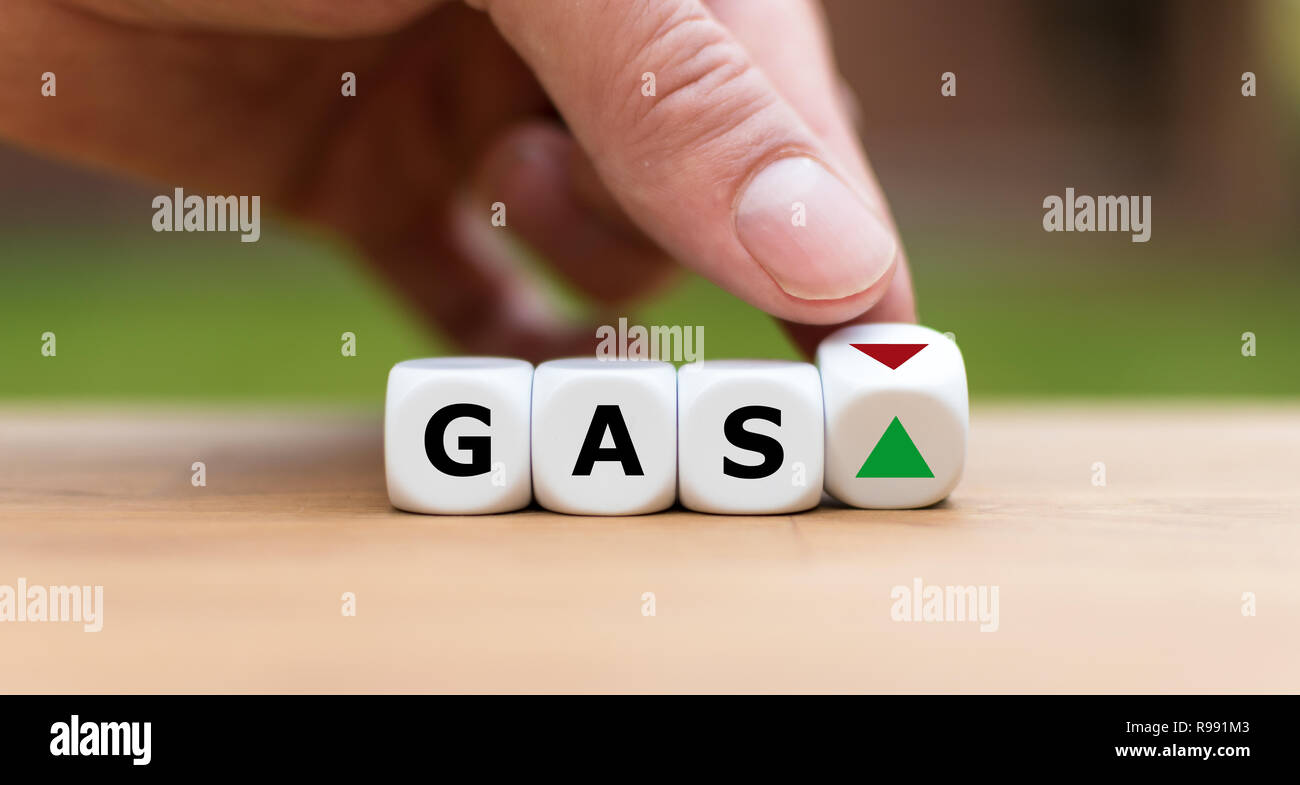Hand is turning a dice and changes the direction of an arrow symbolizing that the price for gas is changing the trend and goes up instead of down (or Stock Photo