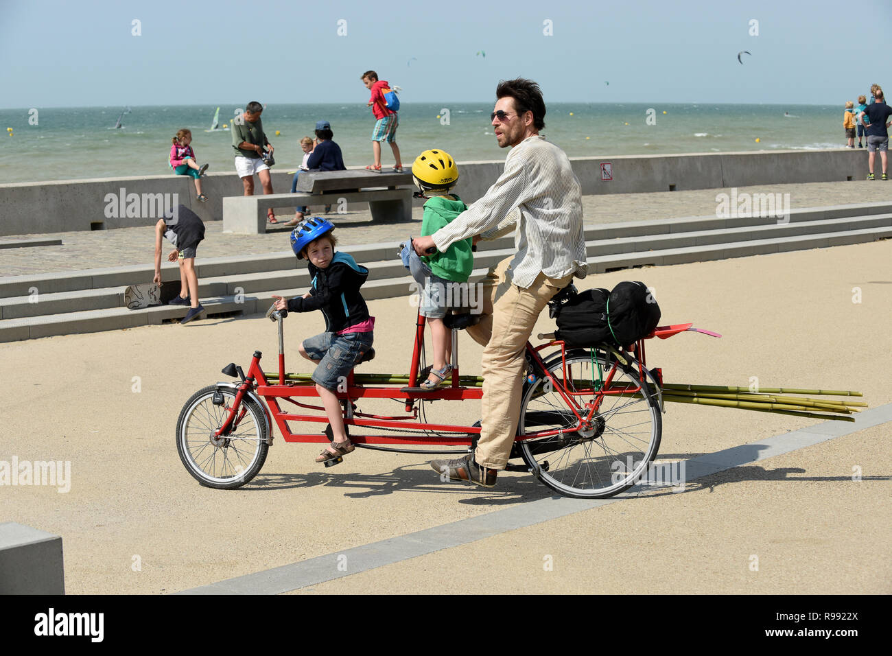 Man riding bike with two children on board at Wissant in northern France Stock Photo