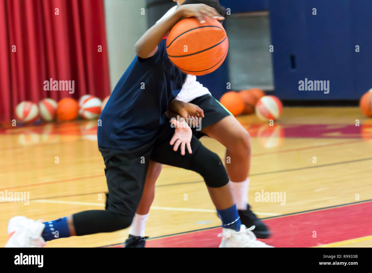 Two teenage male basketball players doing a one on one drill indoors at